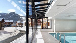 Ein modernes Hallenbad mit Blick auf verschneite Berge und einen klaren Himmel.