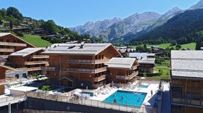 A wooden chalet-style hotel with multiple balconies, a swimming pool, and mountain views. - Wifi, swimming pool, sauna, hammam, tv, ski locker, 45-50m², La Clusaz (La Clusaz)