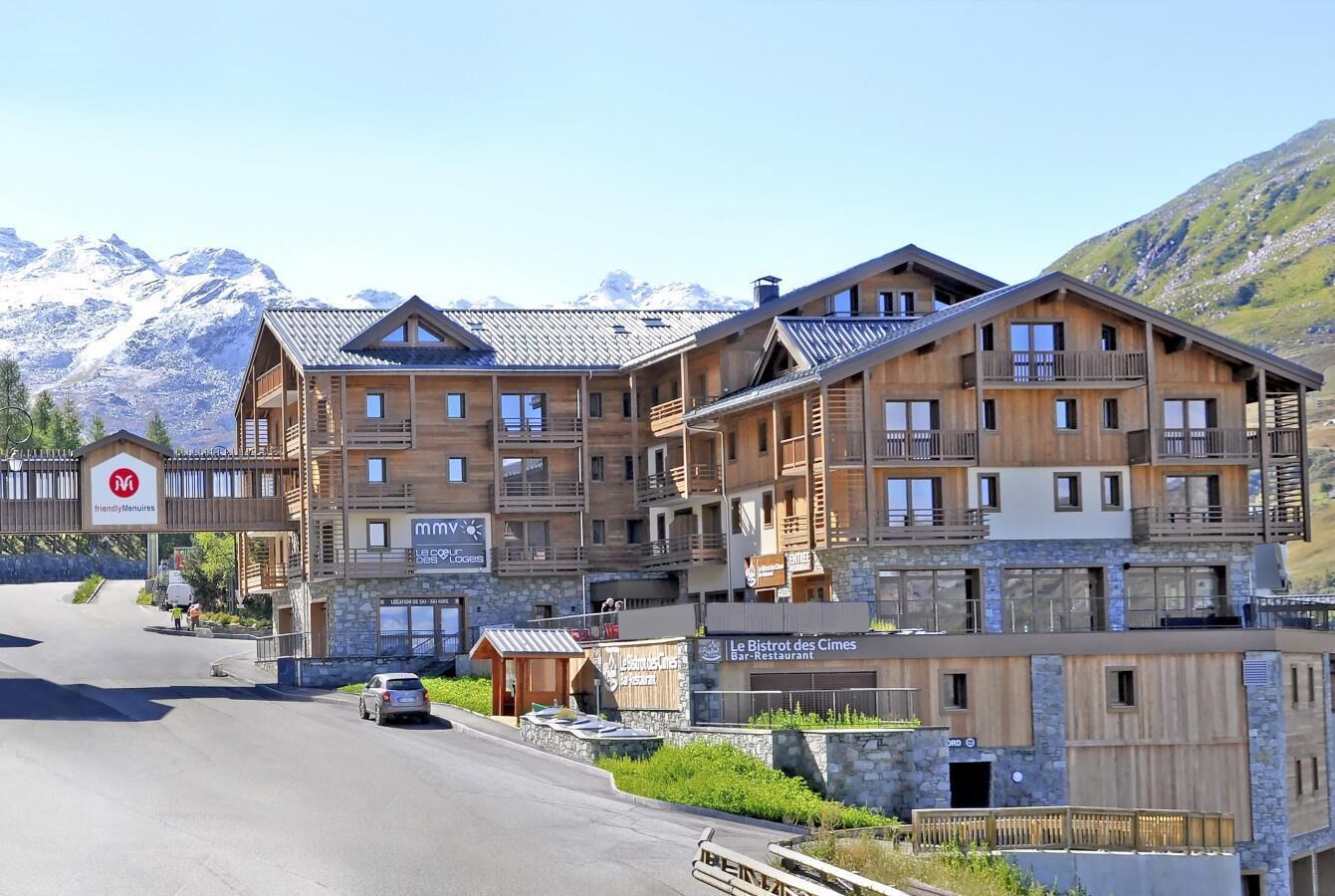 Ett hotell med flera våningar, en träfasad, balkonger och en bergskedja som bakgrund.