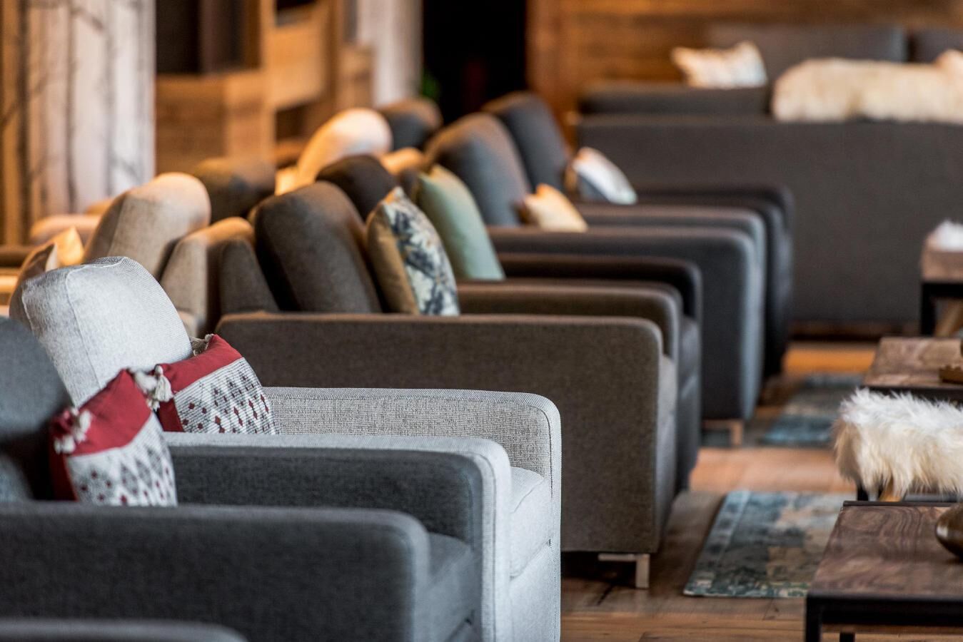 Eine Reihe von Sofas mit verschiedenen Kissen, ein Holzboden und ein Fell auf einem Tisch.