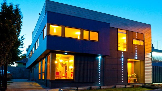A modern hotel with a two-story structure, large windows, and a visible restaurant area with bright interior lighting. - Hotel Ilaia (Punta Arenas)