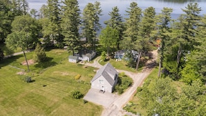 An aerial view of a residential area with a large house, a smaller house, and a dock extending into a lake. - Lakefront haven near Pleasant Mt-central location-25 mi. to N.Conway (Bridgton)