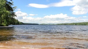 A lake with a sandy beach and trees on the left. - Lakefront haven near Pleasant Mt-central location-25 mi. to N.Conway (Bridgton)