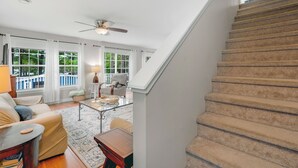 A spacious living room with a staircase, a ceiling fan, and a view of the outdoors. - Lakefront haven near Pleasant Mt-central location-25 mi. to N.Conway (Bridgton)