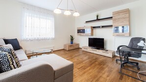 Una sala de estar moderna con sofá, televisor y zona de escritorio.