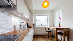 Una cocina moderna con salpicadero de mármol, encimera de madera y ventana con vistas a edificios.