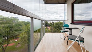 Un balcón con vistas a un parque y edificios, una mesa y dos sillas.