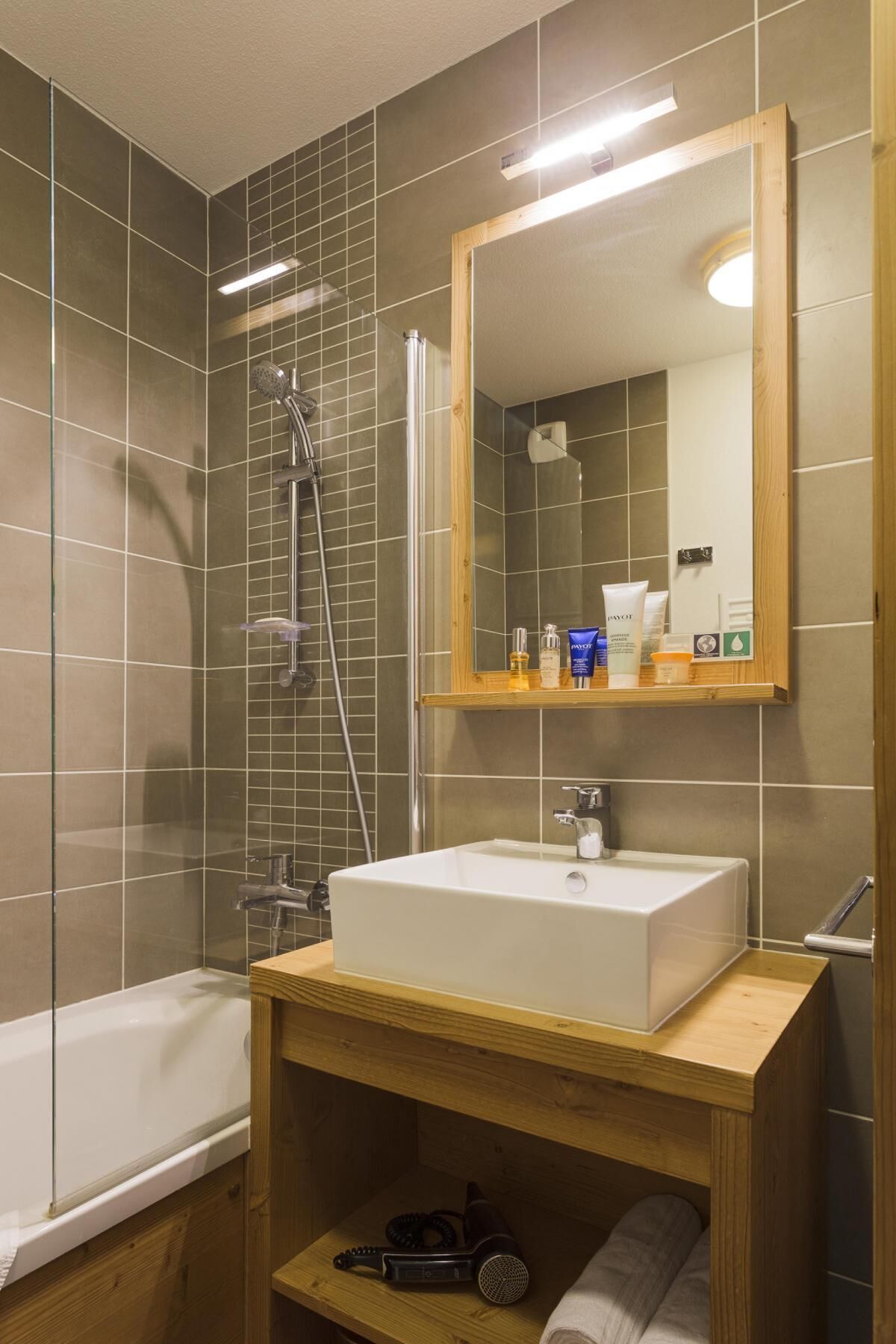 A modern bathroom with a large mirror, a bathtub, and a sink.