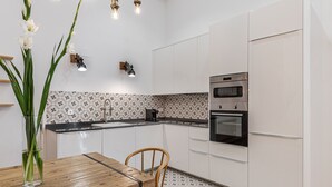 Una cocina moderna con armarios blancos, una mesa de comedor de madera y un salpicadero con diseño.