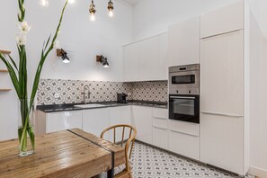 Una cocina moderna con armarios blancos, una mesa de comedor de madera y un salpicadero con diseño.