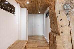 Un pasillo con suelo de madera, paredes blancas y techo de madera.
