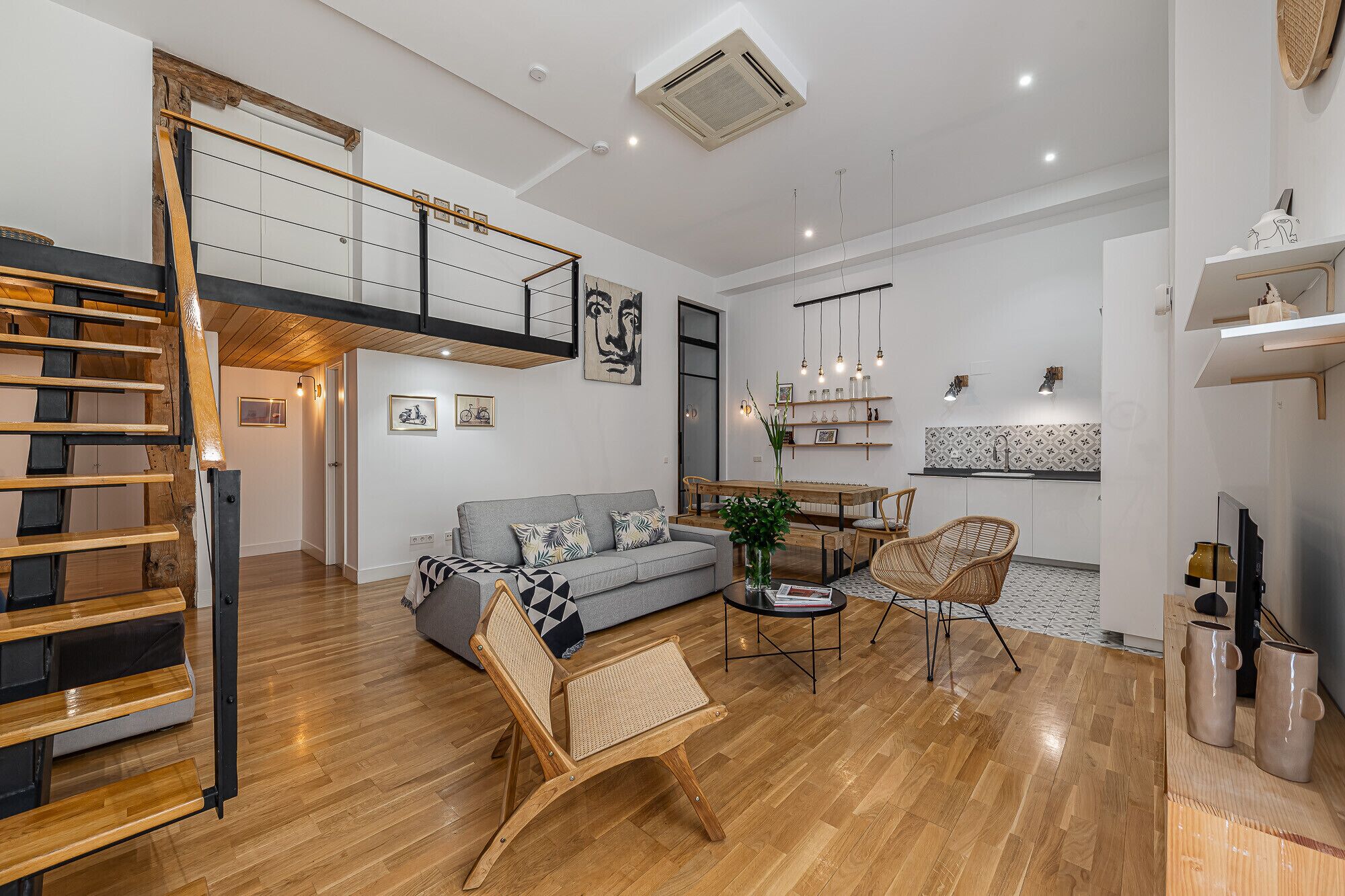 A modern living room with a staircase, a dining area, and a kitchen.