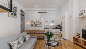 Una sala de estar moderna con un sofá, una mesa de comedor y una cocina al fondo.
