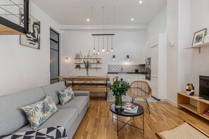 Una sala de estar moderna con un sofá, una mesa de comedor y una cocina al fondo.