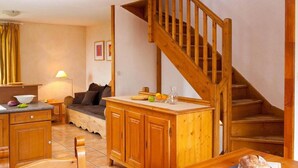 Une cuisine chaleureuse avec des meubles en bois, une table à manger et un escalier.