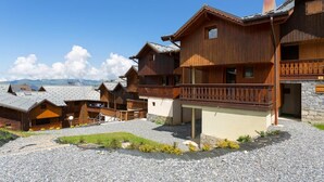 Un chalet en bois doté d’un balcon, de murs en pierre et d’une allée gravillonnée.