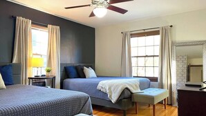 A bedroom with two beds, a ceiling fan, a bedside table with a lamp, and a window with curtains. - Hot Tub | Sauna | 1.1 MI to ND  | Backyard Oasis (South Bend)