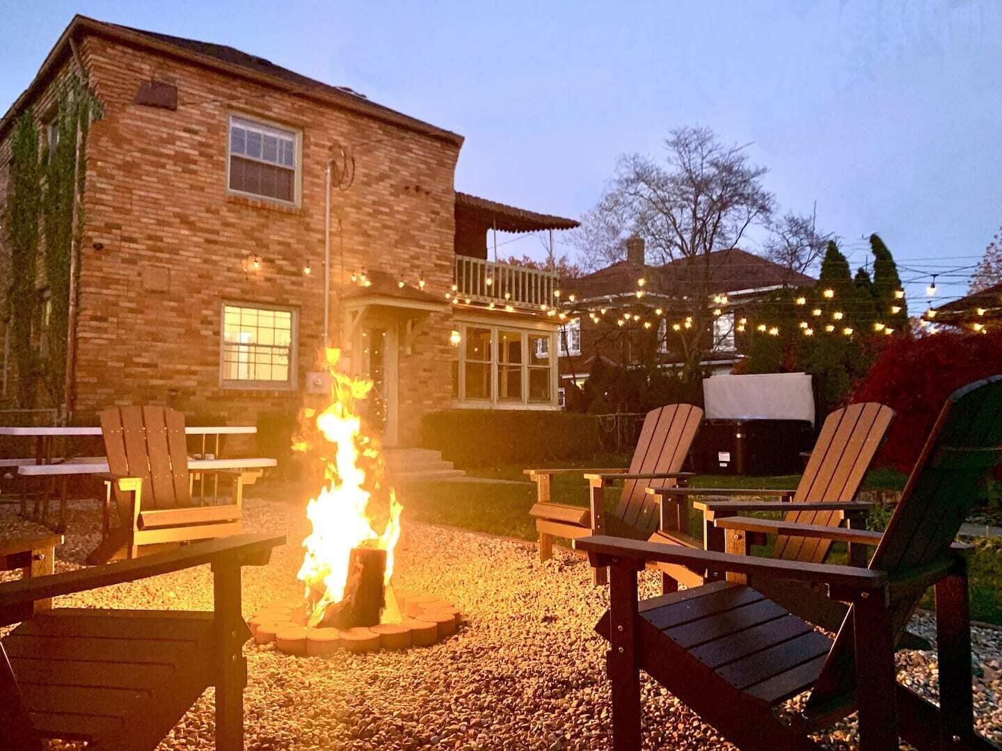 A rustic stone building with a fire pit in the center, surrounded by wooden Adirondack chairs.