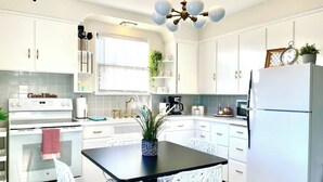 A modern kitchen with white cabinets, a black dining table, and a refrigerator. - Hot Tub | Sauna | 1.1 MI to ND  | Backyard Oasis (South Bend)