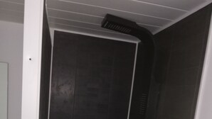 A walk-in shower with dark tiles and a white door. - Charming Duplex 4 people (FLEURY-SUR-ORNE)