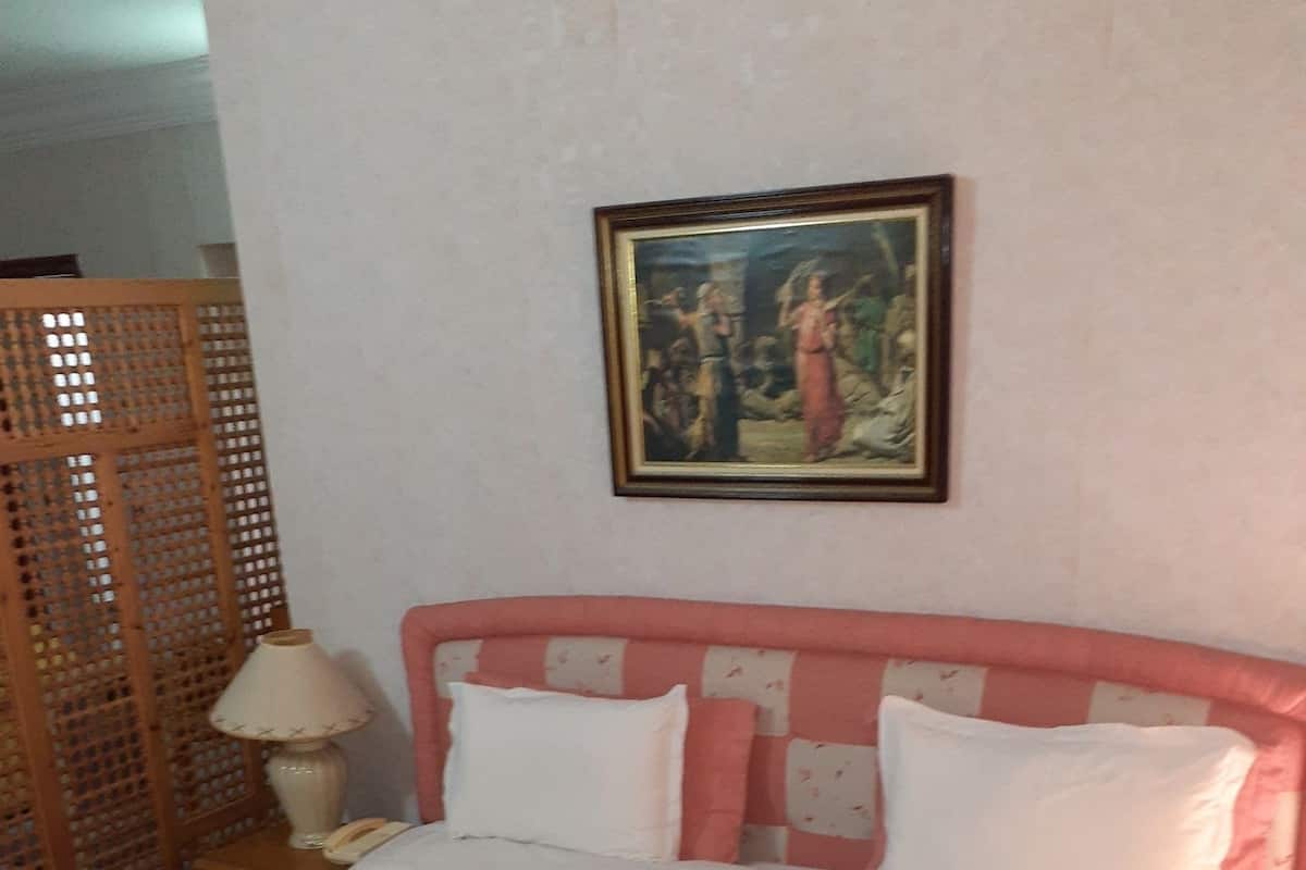 Ein Bett mit einem rosa Kopfteil, weißen Kissen und einer Bettdecke mit Blumenmuster.
