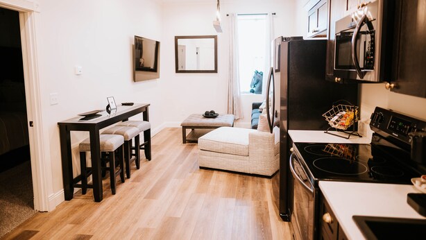 A modern kitchen with a dining area, wooden flooring, and a view to the outside. - Inn On Central (Le Mars)