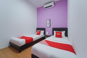 Two single beds with red and white bedding, a purple wall, and a white air conditioning unit. - OYO 89982 Familia motel (Kangar)
