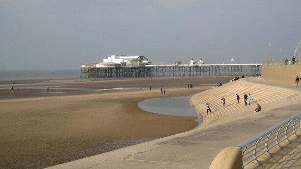 A beach with a pier and a building in the background. - Deneside Guest House (Blackpool)