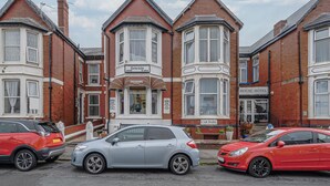A row of terraced houses with a 'House Hotel' sign, a 'Car Park' sign, and a 'Denside' sign. - Deneside Guest House (Blackpool)