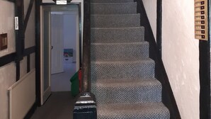 A staircase with a carpeted finish, flanked by white walls with black trim. - Deneside Guest House (Blackpool)