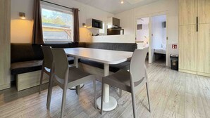 Un comedor moderno con una mesa blanca y sillas grises, un microondas integrado y una ventana con cortinas.