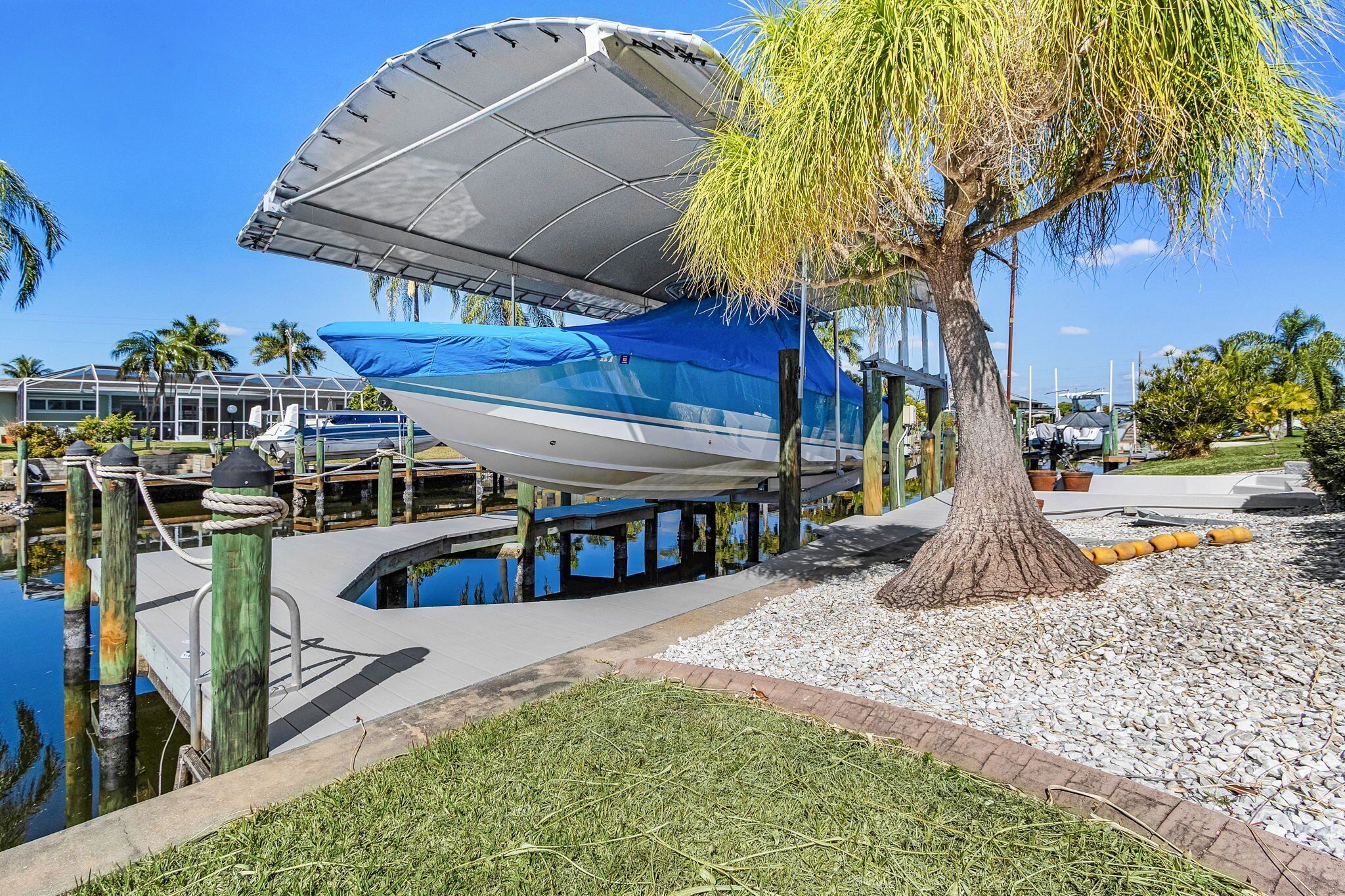 A boat docked under a covered area with a tree nearby.