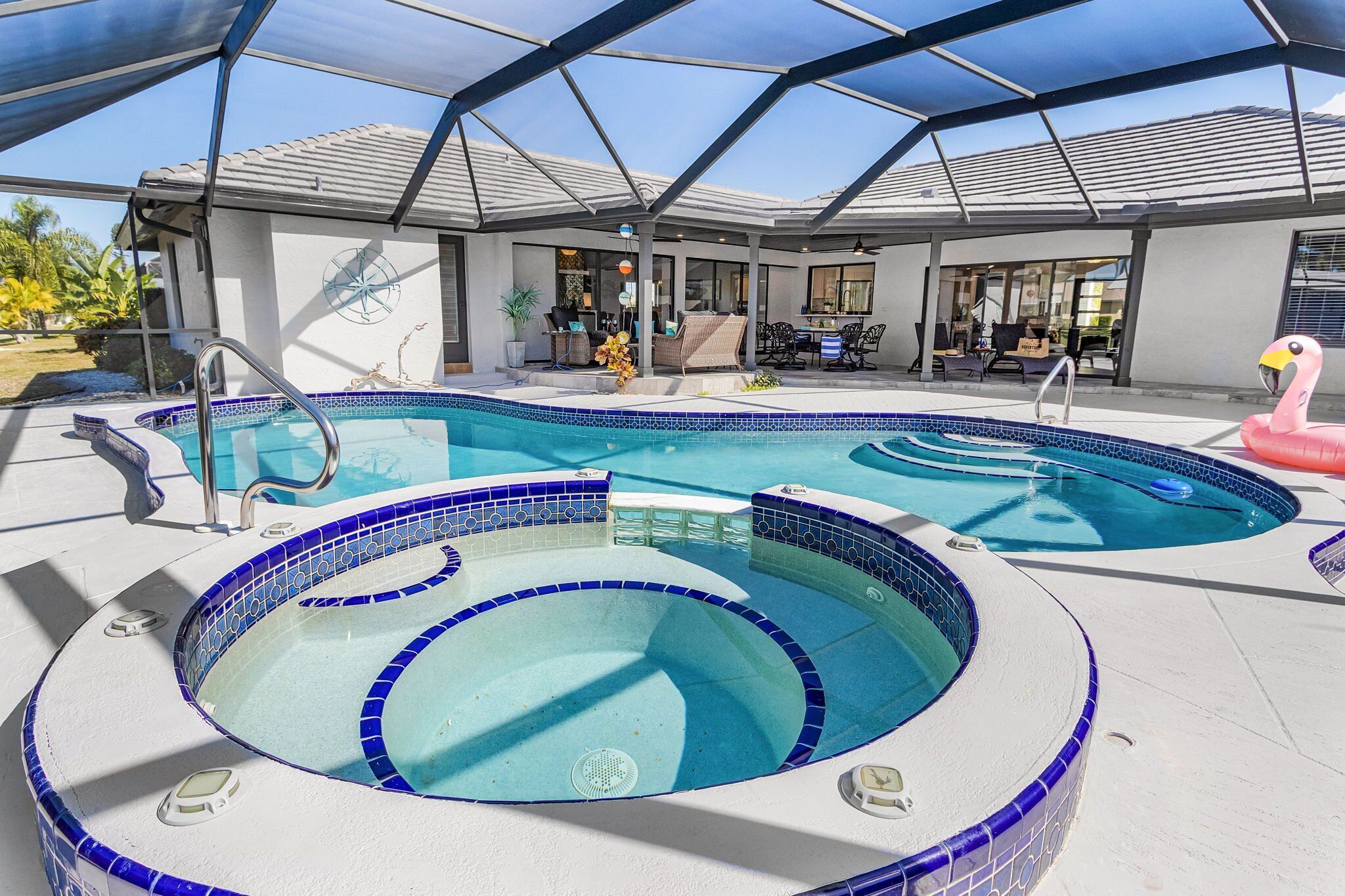 A swimming pool with a hot tub, a covered patio area, and a flamingo decoration.