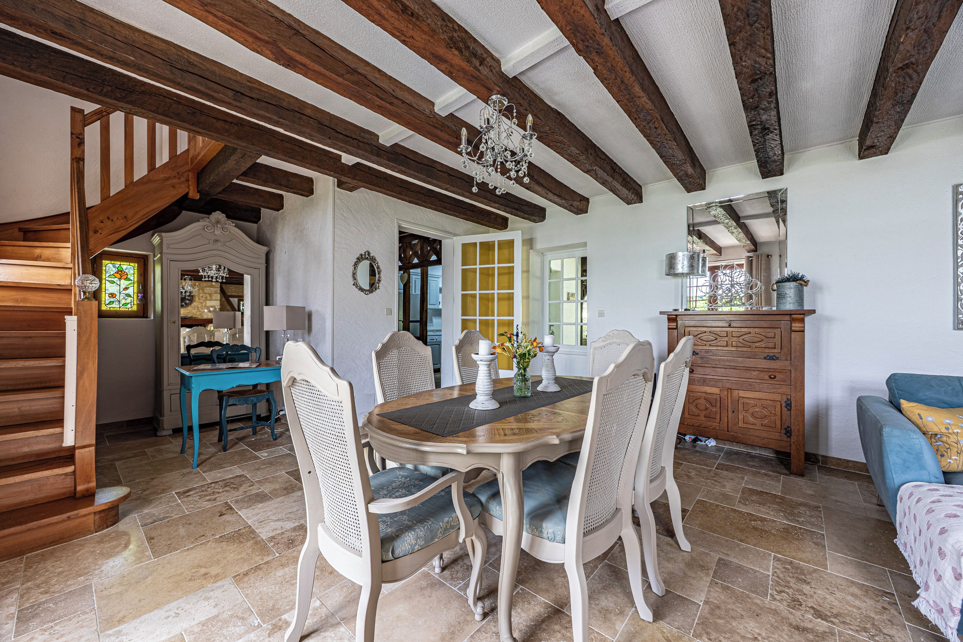 A dining area with a wooden table, chairs, and a chandelier.