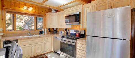 A modern kitchen with wooden cabinets, stainless steel appliances, and a large window providing natural light.