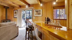A wooden interior with a bar area, seating, and framed artwork. - Switzerland SKI Chalet #845 (Big Bear Lake)