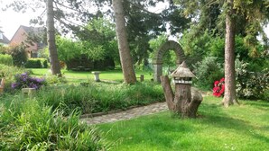 Un sendero de jardín que conduce a un arco de piedra rodeado de abundante follaje y plantas en flor.