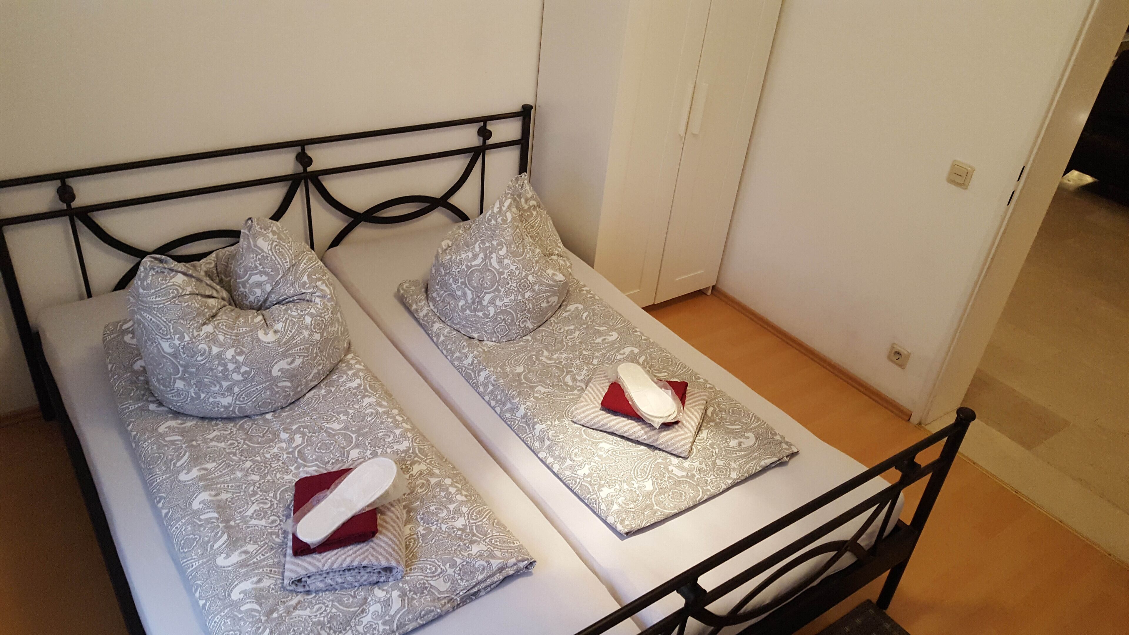 A single bed with a metal frame, two pillows, and a folded blanket.