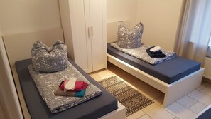 A bedroom with two beds, each with patterned bedding and pillows. There is a wardrobe and a patterned rug on the floor. - 4 Jahreszeiten (Lauenau)