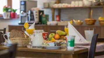 Une table de petit-déjeuner avec divers aliments, une carafe de lait et un verre de jus d’orange.