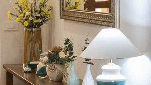 A wooden console table with a mirror, a white lamp, and various decorative items including flowers and plants. - Imperial house (Plitvicka Jezera)