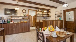 A cozy kitchen with wooden cabinets, a dining table set with breakfast items, and a clock on the wall. - Imperial house (Plitvicka Jezera)