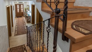 A staircase with ornate metal railings leading to a landing with a wooden bench and a rug. - Imperial house (Plitvicka Jezera)