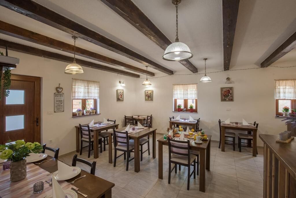 A dining area with wooden tables and chairs, pendant lights, and framed pictures on the walls.