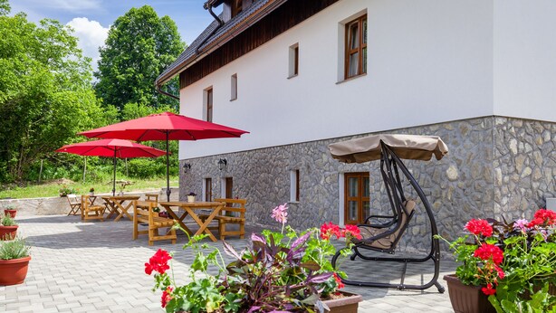 An outdoor patio area with a stone wall, wooden furniture, and potted plants. - Imperial house (Plitvicka Jezera)