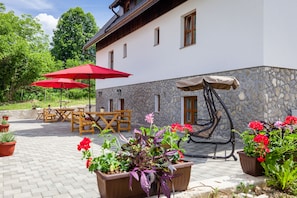 An outdoor patio area with a stone wall, wooden furniture, and potted plants. - Imperial house (Plitvicka Jezera)