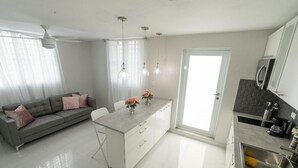 A modern kitchen with a central island, a dining area with a sofa, and a large window with sheer curtains. - Beautiful modern apartment close to airport and the beach (Cangrejo Arriba, Carolina, Puerto Rico)