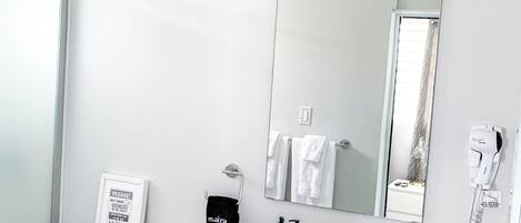 A modern bathroom with a toilet, bidet, sink, and mirror.