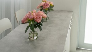 A dining area with a long table, three pendant lights, and two vases with flowers. - Beautiful modern apartment close to airport and the beach (Cangrejo Arriba, Carolina, Puerto Rico)