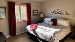 Una camera da letto con un letto, una finestra con tende, una lampada a parete e un quadro incorniciato.